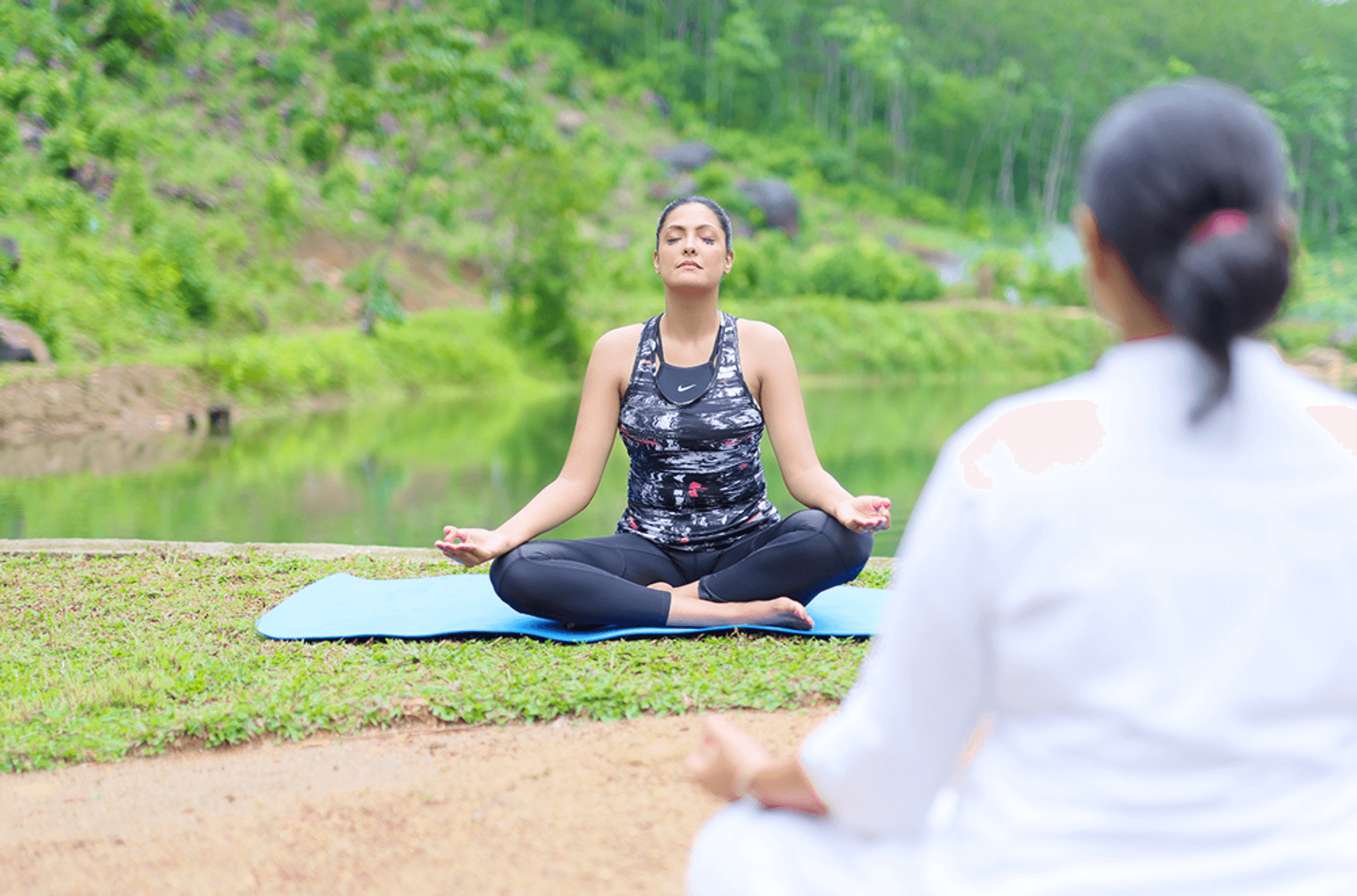 Guest meditating on a yoga mat surrounded by scenic greenery